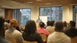 © Makmur - Man speaks to seated audience in brightly lit room with wood ceiling