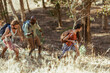 © Marko Geber - Group of friends hiking uphill with trekking poles in forest