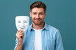 © Nataliya - Man posing with smiling theater mask against a green background. Concept of psychology, identity, personal growth and emotional awareness.
