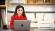© Emanuel - Young Hispanic woman working remotely with her laptop from home. Concept of remote work, digital jobs, and technology at home.
