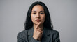 ©  Kibria Islam - Businesswoman with long dark hair rests her chin on her index finger while contemplating a strategic decision in a studio setting.
