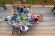 © Halfpoint - Above shot of family eating at barbecue party dinner on patio, little girl eating roasted corn and enjoying it.