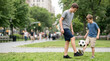 © Xenia - Two brothers playing soccer in a city park. Older sibling teaching younger boy to juggle a ball