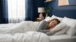 © Megin Design - Woman sleeping in a comfortable bedroom with white linens. Restful sleep in a temperature controlled home environment. Air conditioning and comfort concept