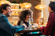 © Santi Nuñez/Stocksy - Friends laughing together enjoying dinner in restaurant