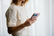 © OchreOchre/Stocksy - Woman Holding Smartphone Near Window in Soft Light