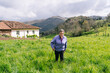 © Daniel Gonzalez/Stocksy - Elderly cheesemaker woman standing in green rural field