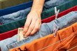 © Basil Pind/Stocksy - Hand placing money into denim pocket on clothesline
