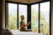 © Guille Faingold/Stocksy - Woman texting by smartphone and laughing at hotel room