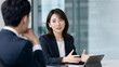 © Yka - 会議室でタブレットを使い説明する日本人女性ビジネスパーソン
