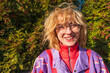 © Basil Pind/Stocksy - Happy woman with windblown hair in colorful sweater outdoors