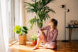 © Maria Sher/Stocksy - Woman Sitting on Floor With Plants and Sunlight in Home Space