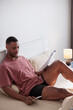 © Jovo Jovanovic/Stocksy - Man in bed reviews documents and uses phone.