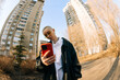 © Alexey Kuzma/Stocksy - Young Person Checks Phone Near Tall Buildings in the City