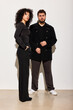 © Javier Díez/Stocksy - Couple stands together in modern space with neutral background
