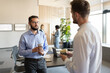 © Niyaz Tavkaev/Stocksy - Male coworkers speaking during coffee break