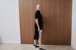 © Serge Filimonov/Stocksy - Stylish woman in black dress pose over wooden wall