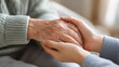 © Aysha - Senior woman with daughter holding hands at home, closeup