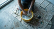 © Volha - Overhead view of person kneeling on drop cloth cleaning paint brushes in a yellow bucket of soapy water