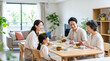 © Blue Studio - 家族がリビングやダイニングで食事を楽しむ笑顔のライフスタイル 三世代