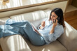© Miljan Živković - Woman relaxing on sofa talking on smart phone