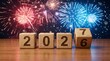 © Pixim Stock - Happy new year 2027 transition with fireworks and wooden cubes showing 2026 then 2027 on wooden surface.