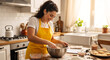 © NeuroCake - Smiling woman mixing dough in a metal bowl in the kitchen. Female baker in a yellow apron making homemade cookies. Domestic culinary hobby