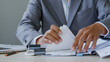 © WARAPHON - Businessman sorts papers at desk. Hands grip stacks of documents with focus. Office environment suggests planning or review. Scene conveys diligence and organization