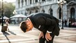 © meka - Man in Suit Bending Over in City Street Sunlight.
