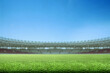 © Leo Lintang - Low-angle view of a vibrant green grass field inside a large, empty sports stadium under a clear blue sky