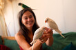 © Solid photos - Young woman playing with her pet parakeets at home