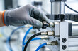 © Snide12 - Gloved hand adjusts knob on industrial pneumatic equipment with blue hoses