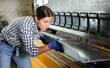 © JackF - Young woman worker bends sheet of metal under press in metallurgical workshop