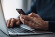 © oksa_studio - Senior elderly hands using smartphone and laptop for digital connectivity