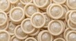 © ProNoJoy - Many unwrapped latex condoms arranged in a dense pattern forming a textured background of translucent circular shapes for sexual health and safety education