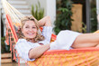 © Westend61 - Portrait of smiling mature woman relaxing in hammock on terrace