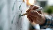 © Evgeniia - Hand marking completed tasks on a checklist calendar with a green marker, illustrating ADHD habit tracking, productivity improvement, goal achievement and personal organization