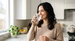 © 56Tania - Smiling woman drinking water in modern bright kitchen setting