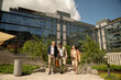 © Guirado - Corporate employees chatting and laughing as they leave the office after work on a sunny day