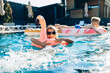 © Petro - Happy girl on a flamingo float playing in refreshing blue water with siblings enjoying a sunny day at the resort pool