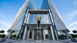 © solom - Wide angle shot of a professional window cleaner standing on a high ladder cleaning the glass facade windows of a modern office corporate building skyscraper