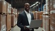 © aref - Confident manager with laptop controlling inventory in modern distribution center