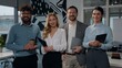 © Yuliia - Multiethnic business team posing in office four multiracial businesspeople diversity colleagues standing in company agency firm smiling together businesswomen with businessman smile looking at camera