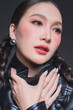 © whyframeshot - Low angle of confident Asian woman in leather jacket for high fashion cosmetics marketing campaign luxury streetwear aesthetic female empowerment concept edgy portrait studio