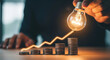 © Dudu - Rising Market Graph Idea Innovation Business Growth Finance Investment With Lightbulb and Coins Showing Investment Growth and Financial Concept
