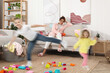 © New Africa - Family with hyperactive children. Tired mother sitting on sofa while her kids having fun