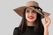 © Pixel-Shot - Beautiful young woman in hat with red lips on grey background