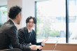 © kapinon - 広いオフィスで打ち合わせをする若い営業と社長　提案営業や部下の企画の説明など前向きな打ち合わせイメージ　上半身