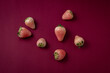 © Cavan Images - Fresh white strawberries on luxury dark burgundy red paper background