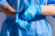 © Mikhailov Studio - Healthcare professional putting on blue medical gloves on white background with copy space